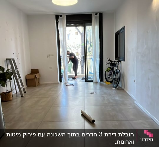 חדר ריק עם אדם ליד חלון, סולם, קופסאות ואופניים